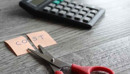 Scissors cutting a note with cost in it, money moves to control the finances in your business