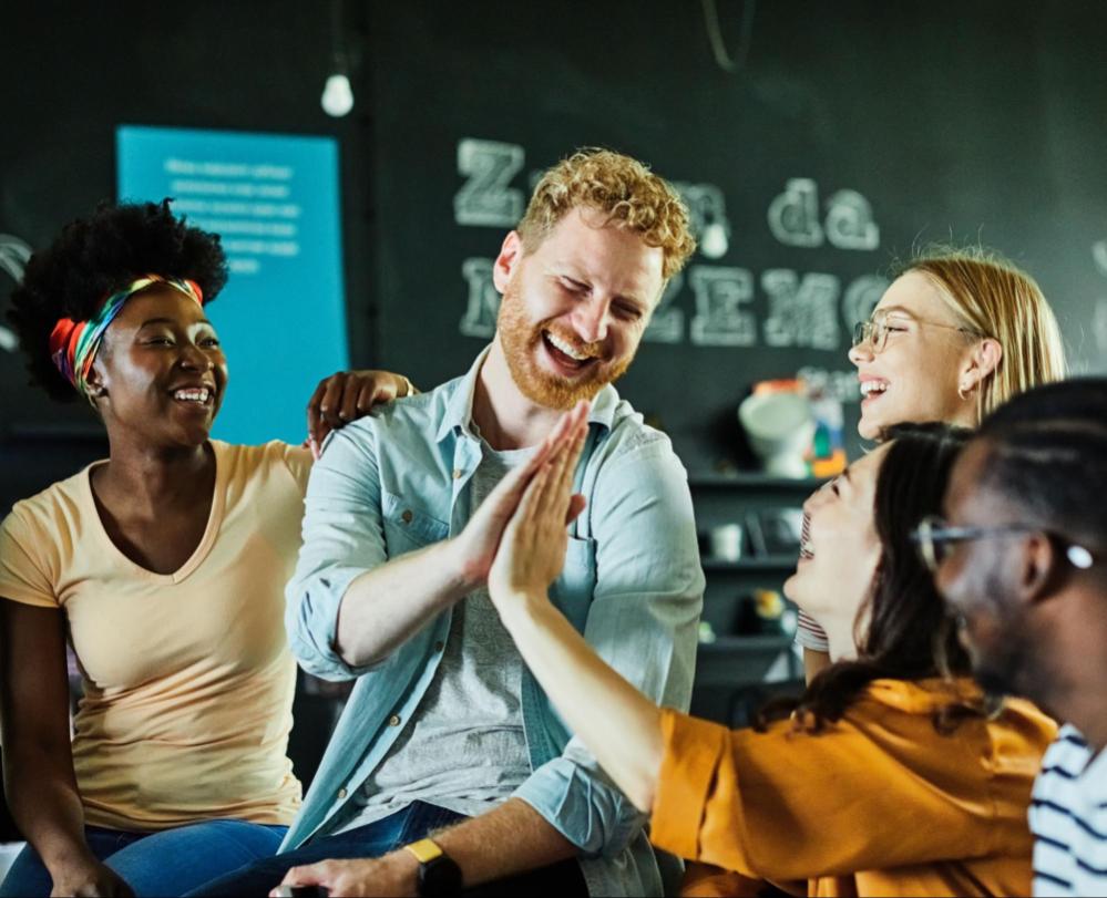 Diverse employees in an office smiling and hi fiving