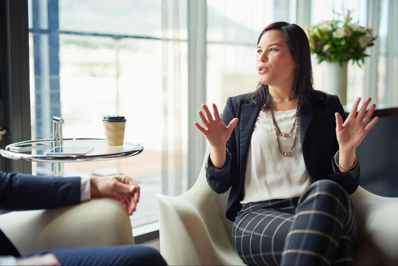 Young female professional in a casual seating setting explaining something to a colleague